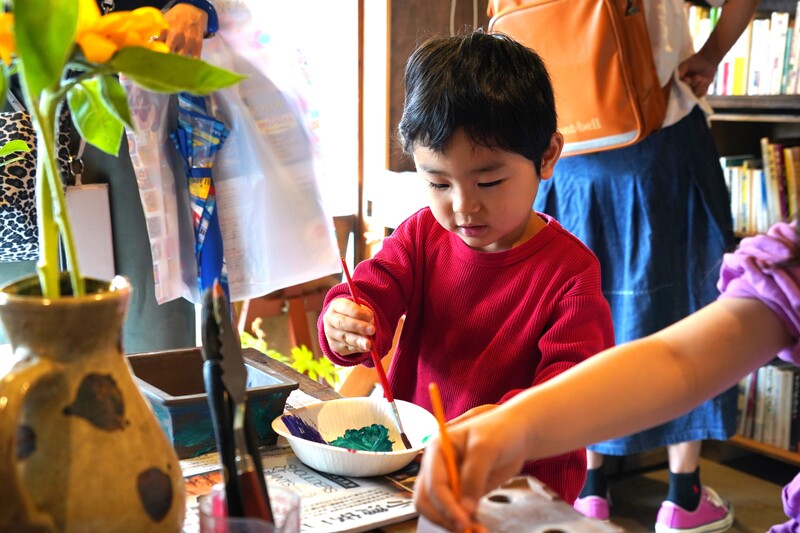 子供が鉢に色を付けている様子