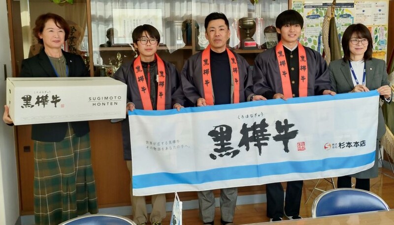 黒樺牛とかかれた幕をもって集合写真を撮っている様子